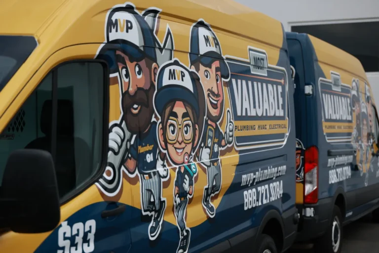 Two yellow and blue vans feature cartoon illustrations of workers and bold text advertising MVP Valuable Plumbing, HVAC, and Electrical services.