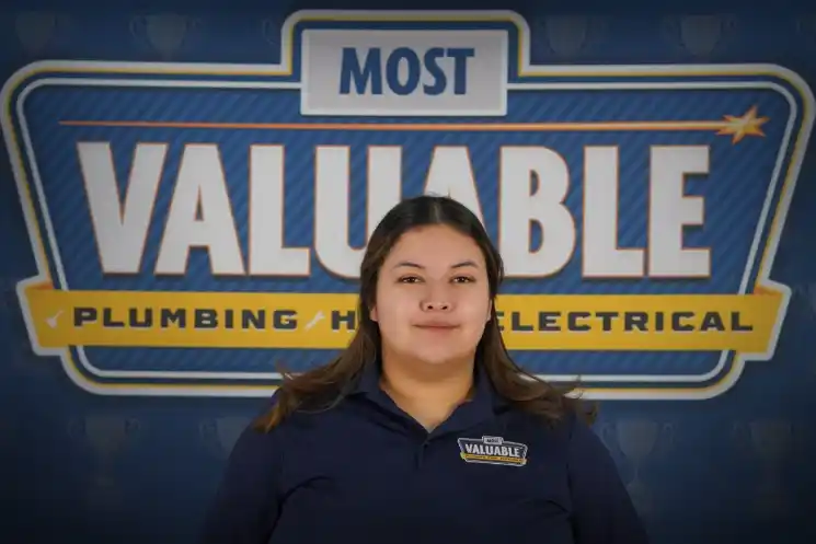 A person in a "Most Valuable" uniform stands in front of a backdrop that reads "Most Valuable Plumbing HVAC Electrical," ready to help you meet the team dedicated to quality service.