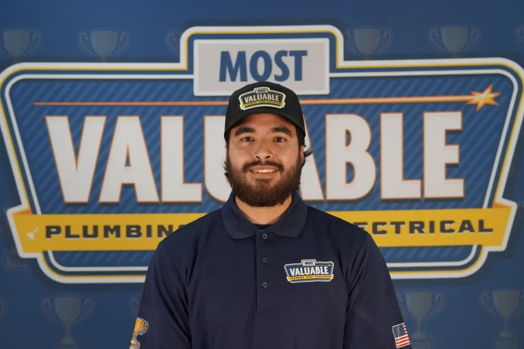 Meet the team: A man in a "Most Valuable" uniform and hat stands proudly in front of a backdrop that reads "Most Valuable Plumbing Electrical.
