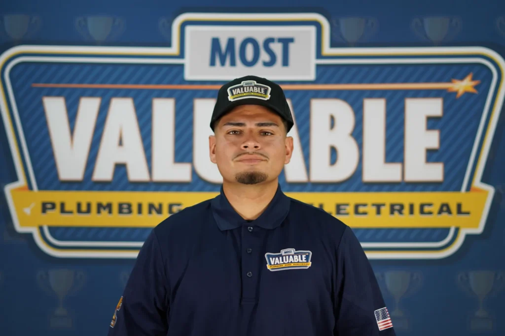 Meet the team: A man in a navy blue "Most Valuable" uniform and cap stands in front of a backdrop with the words "Most Valuable Plumbing & Electrical.